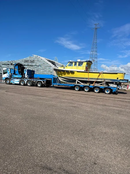 Keltainen vene perävaunun päällä satama-alueella.